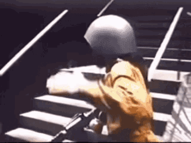 a person wearing a helmet is standing on a set of stairs holding a gun .