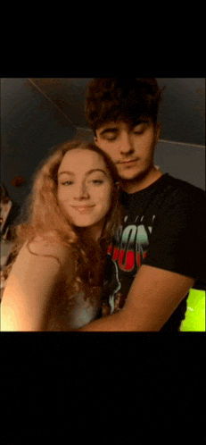 a man and a woman are posing for a picture and the man is wearing a shirt that says ' a ' on it