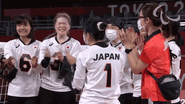 a woman wearing a japan jersey is surrounded by other people