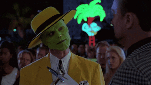 a man in a yellow suit with a green mask is talking to another man