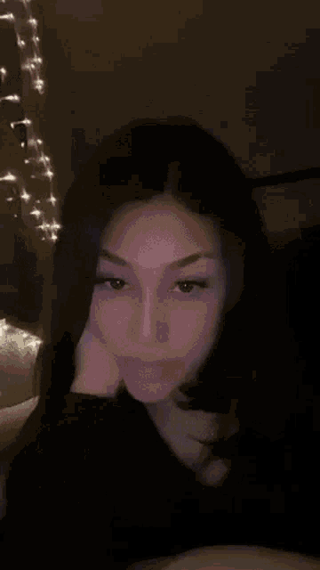 a woman is sitting on a couch with her hand on her face and looking at the camera .