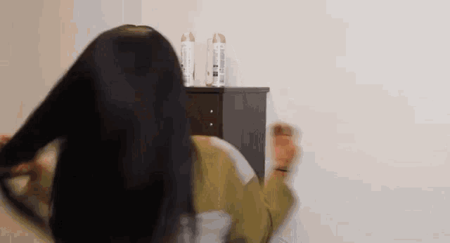 a woman is standing in front of a wall with her hair blowing in the air .