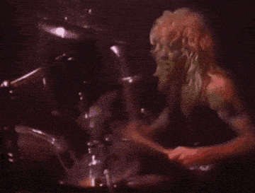 a man is playing a drum set in a dark room