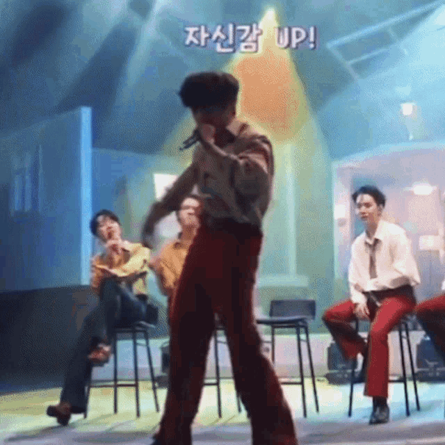 a man singing into a microphone with a sign above him that says ' up '
