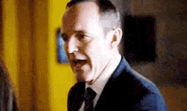 a man in a suit and tie is making a funny face with his mouth open .