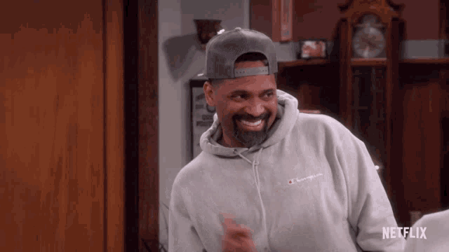 a man wearing a champion hoodie and a hat is smiling