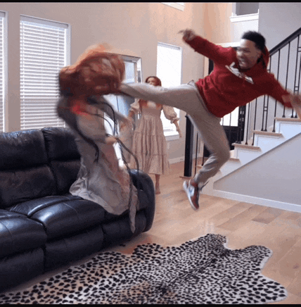 a man in a red hoodie kicking a woman in the face