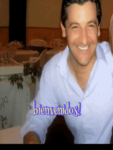 a man in a blue shirt is smiling with the words bienvenidos in the corner