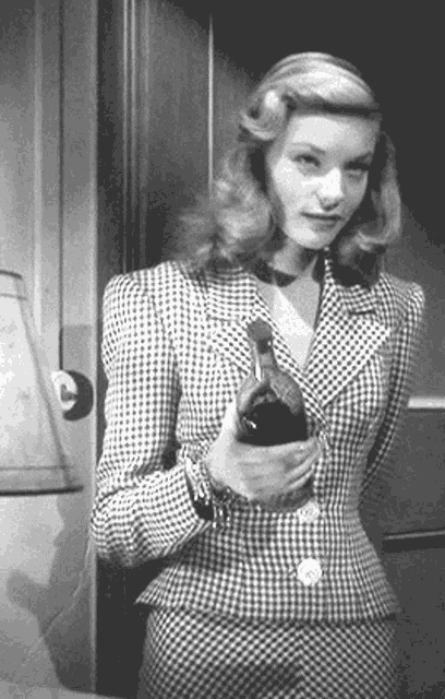 a woman in a gingham suit is holding a bottle of wine .