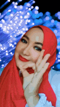 a woman wearing a red head scarf is giving the ok sign