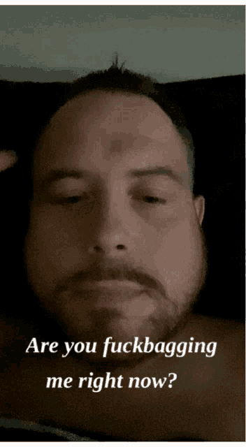 a man with a beard is laying in bed with the words " are you fuckbagging me right now " above him
