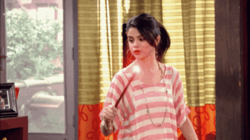a woman in a pink and white striped shirt is standing in front of a window