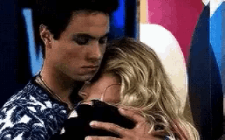 a man and a woman are hugging each other in a room . the man is touching the woman 's face .