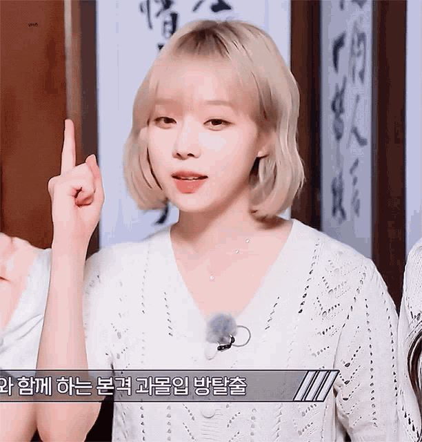 a woman in a white sweater is pointing up