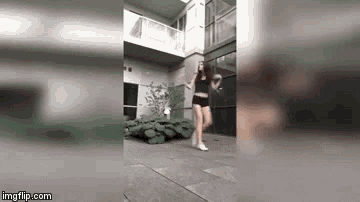 a woman is dancing in front of a building on a sidewalk .