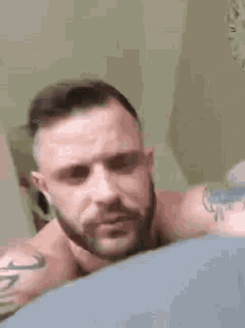 a man with a beard is laying on a bed .