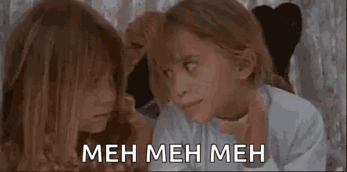 two little girls are laying next to each other on a bed .