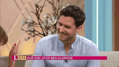 a man is sitting on a couch talking to a woman and smiling .