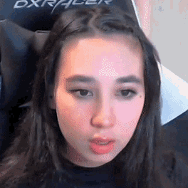 a close up of a woman 's face while sitting in a chair with the word dxracer on it .