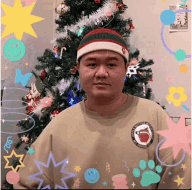a man in front of a christmas tree wearing a beanie