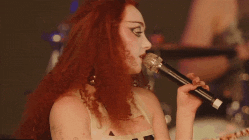 a woman singing into a microphone with a leopard print shirt on