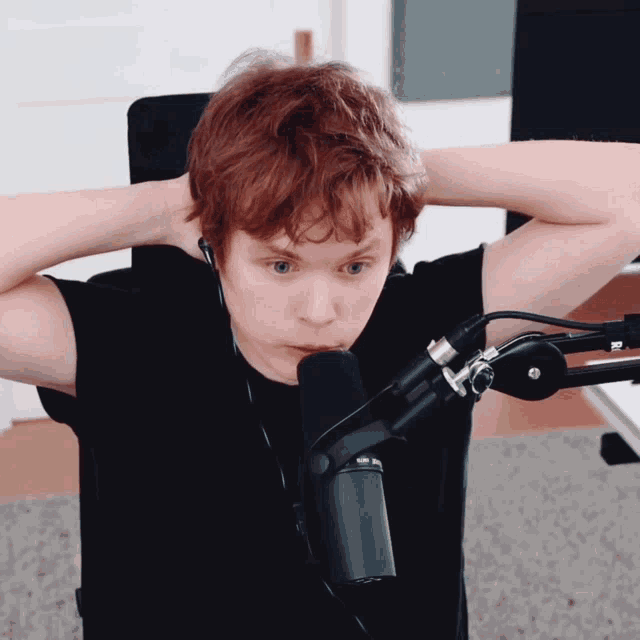 a young man with red hair is standing in front of a microphone