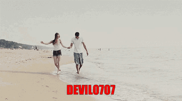 a man and a woman walking on a beach with devil0707 written in red