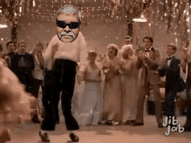 a man with a mustache is dancing in front of a crowd of people .