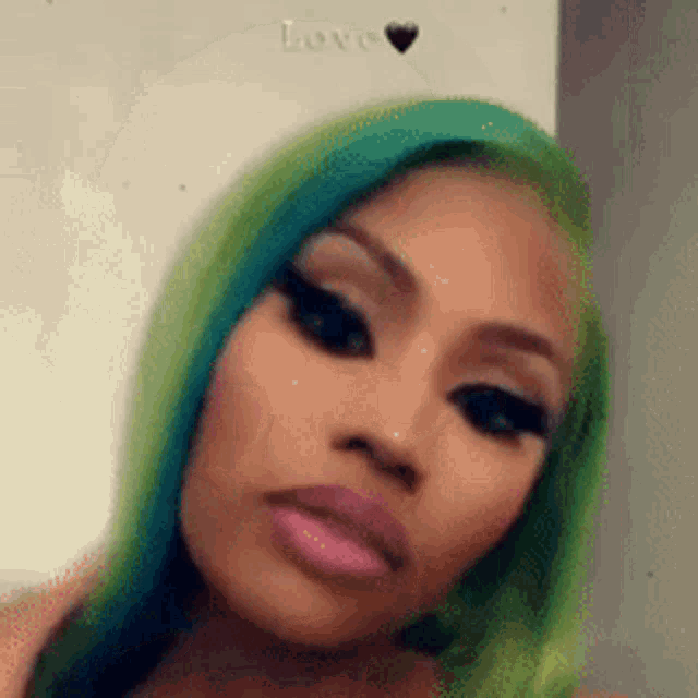 a close up of a woman 's face with green hair and pink lips