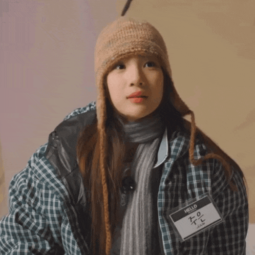 a girl wearing a plaid jacket and a name tag that says hello