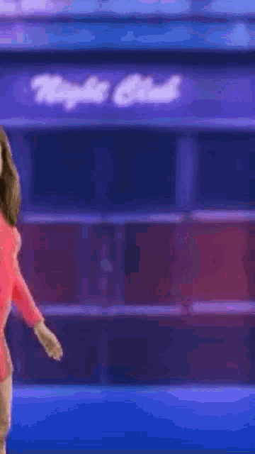 a woman in a pink dress is standing in front of a neon sign that says bad bitch