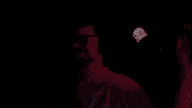 a man wearing headphones and glasses is sitting in a chair in a dark room .