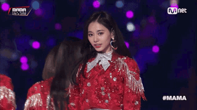 a woman in a red sequined jacket stands on a stage with a microphone