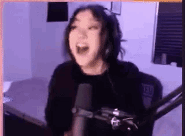 a woman in headphones is screaming into a microphone .