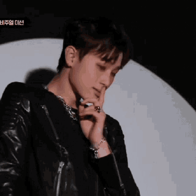 a young man in a black leather jacket is looking down