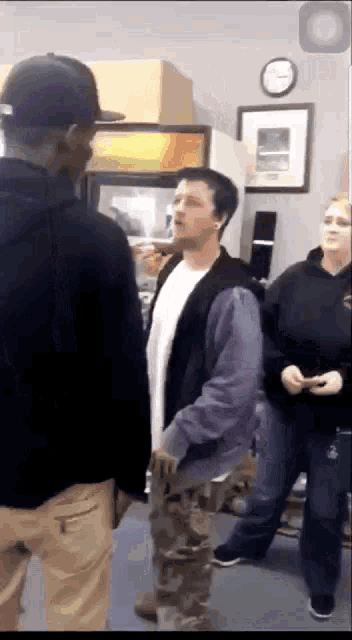 a man in a purple jacket is talking to another man in a black hat