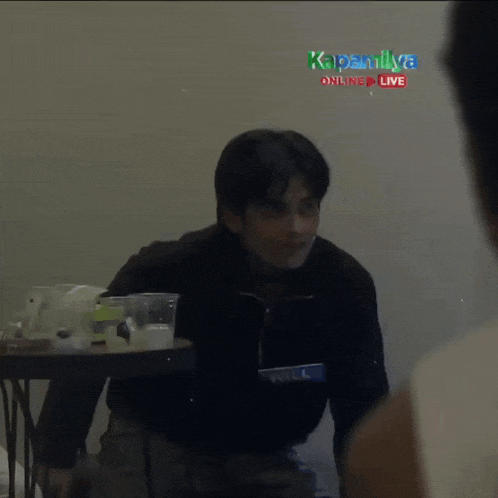 a blurred image of a man standing in front of a table with a sign that says kapamilya online live