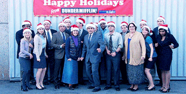 a group of people standing in front of a sign that says happy holidays