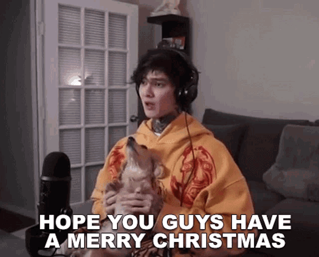 a man wearing headphones is holding a dog in his arms and saying `` hope you guys have a merry christmas ''