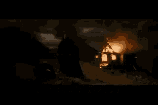 a man is standing in front of a burning house in the dark with the words `` you dare to use my own spells '' .