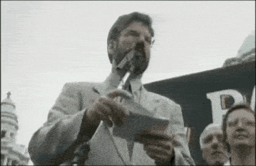 a man in a suit is giving a speech in front of a microphone .