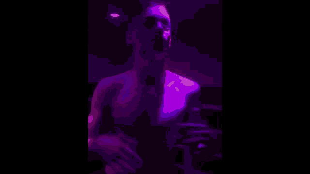 a man is dancing in a dark room with purple lights behind him .