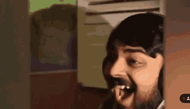 a man with a beard is sticking his tongue out while peeking out of a door .