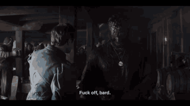 a man in a blue shirt says fuck off bard in a dark room