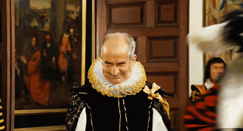a man in a black and white costume with a yellow collar looks at the camera