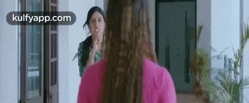 two women are standing next to each other in a room and talking .
