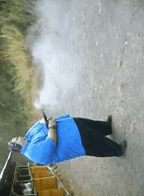 a man in a blue shirt is laying on the ground with a gun in his hand