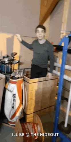 a young boy is standing in a room filled with lots of golf clubs and a golf bag .