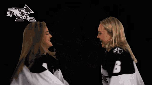 two women wearing jerseys that say proud on them are hugging each other