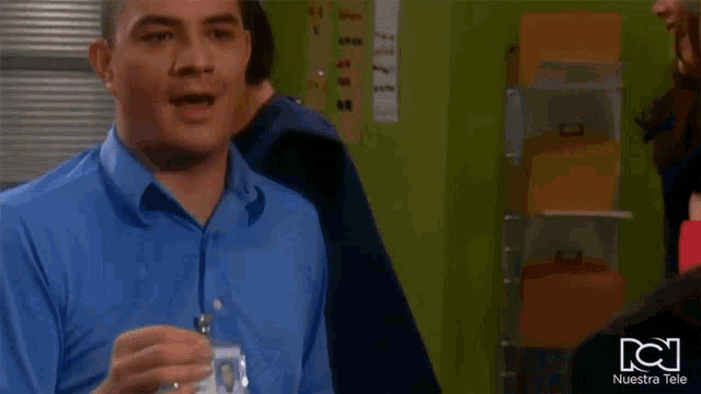 a man in a blue shirt with a name tag that says " nuestra tele " on it